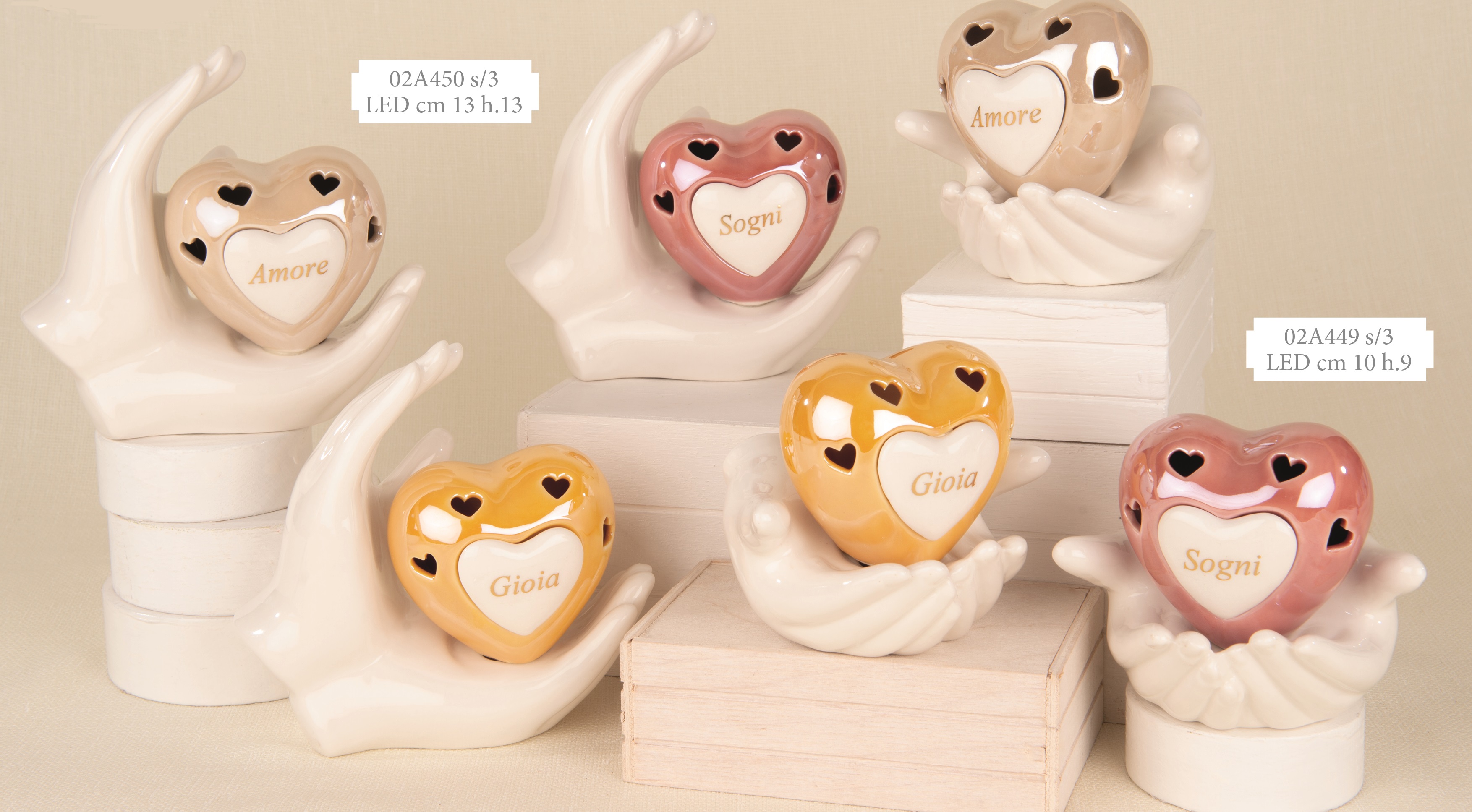 Gruppo di bomboniere a forma di cuore in ceramica color pastello con luce LED, sorrette da mani bianche stilizzate, ideali per eventi eleganti.