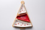 Piatto da portata o vassoio natalizio a tre scomparti, a forma di albero di Natale, su una base di legno chiaro. I tre scomparti in ceramica/porcellana sono di forma triangolare, disposti orizzontalmente. Lo scomparto centrale è rosso brillante con la sc
