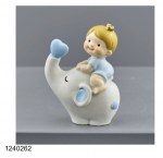 Bimbo con Elefantino Celeste 1240262 Dolce statuina bomboniera per battesimo bimbo raffigurante un neonato con corona dorata seduto sopra un elefante bianco e celeste con proboscide alzata e cuore azzurro.